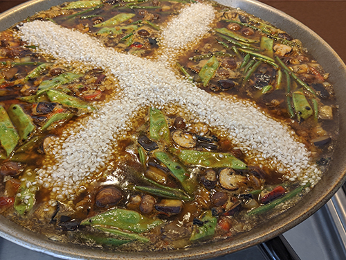 vegetarian paella in the pan with rice cross